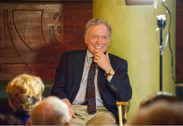 Dick Cavett smiling and sitting before an audience.